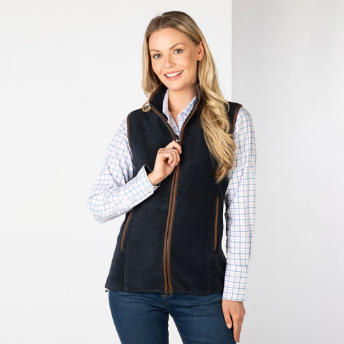 Woman wearing a navy fleece gilet with brown trim over a checked shirt, shown from the front.