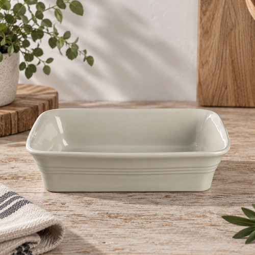 Cream rectangular ceramic baking dish with ribbed detailing, styled on a rustic kitchen worktop