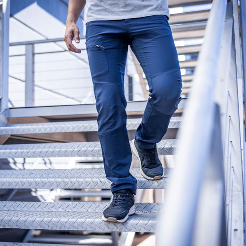 Man wearing blue technical trousers walking down metal stairs, highlighting stretch fabric and zip thigh pocket