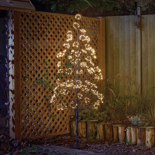 Warm white LED blossom tree light with illuminated branch tips, displayed outdoors beside a garden fence to create a decorative festive lighting feature.