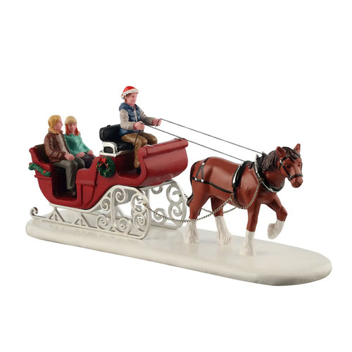 Christmas horse-drawn sleigh figurine with driver in Santa hat and two passengers, featuring festive wreath decorations on a snowy village display base.