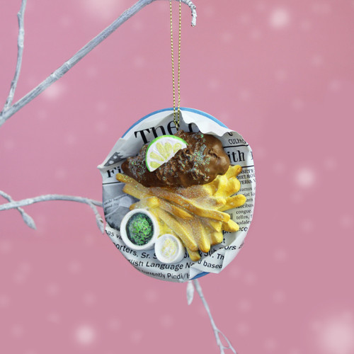 Fish and chips Christmas tree decoration featuring battered fish, golden chips, lemon slice and mushy peas on newspaper.