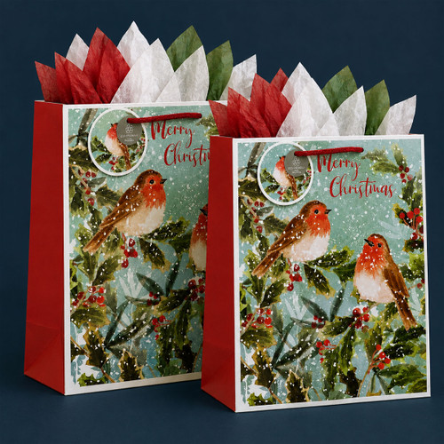 Two Christmas robin gift bags with red, white and green tissue paper on a dark blue background.