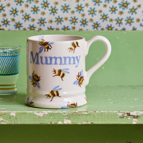 Emma Bridgewater Bumblebee “Mummy” 1/2 Pint Mug styled on a vintage green table, featuring hand-painted bumblebees and soft blue “Mummy” lettering on an ivory ceramic background.