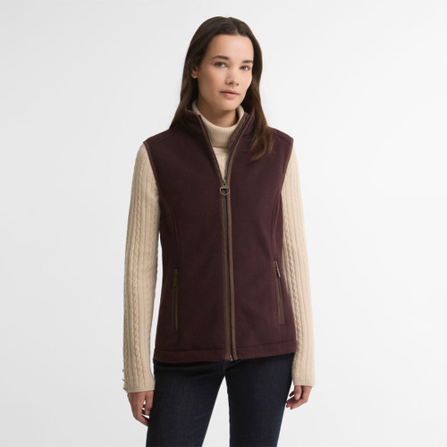 Model wearing the Barbour women's fleece gilet in a rich burgundy colour with a full zip fastening, stand collar and zipped pockets.