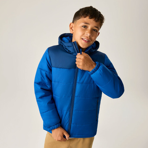 Front lifestyle image of the junior insulated hooded jacket, highlighting the quilted construction, full-zip fastening, zipped hand pockets, and padded hood.