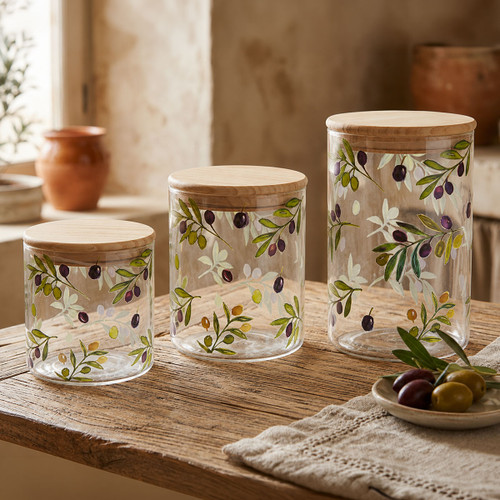 Clear storage canisters with natural bamboo lids in small, medium and large sizes, featuring a colourful olive branch print, displayed together on a rustic wooden table.