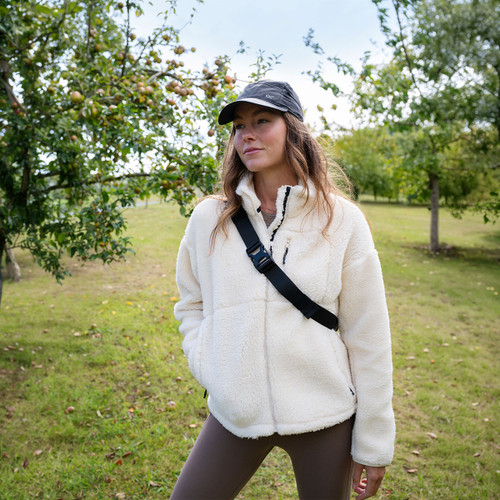 Lifestyle image of a model wearing the Regatta women's light vanilla fleece jacket outdoors with a black cap and crossbody bag.