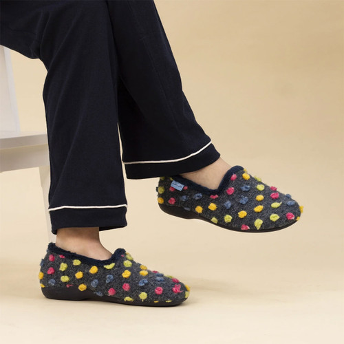 Women's dark grey felt polka dot slippers worn with navy pyjamas, demonstrating the comfortable slip-on fit and cosy indoor style.