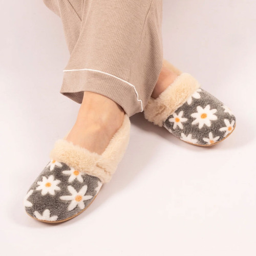 Women's grey daisy print slippers with plush cream faux fur lining worn with lounge trousers, showcasing a cosy and comfortable indoor fit.