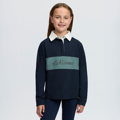 Child modelling a navy LeMieux long-sleeve polo top with white collar, teal chest panel and embroidered logo.