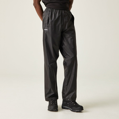 A person wearing black rain trousers and black shoes stands against a plain background. The pants have a shiny texture, conveying a sporty, waterproof vibe.