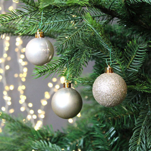 Three pearl baubles hanging from a Christmas tree.