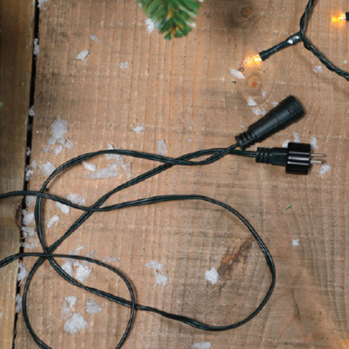 Close-up of a Christmas light extension cable with male and female connectors, designed for linking outdoor LED string lights and festive lighting displays.