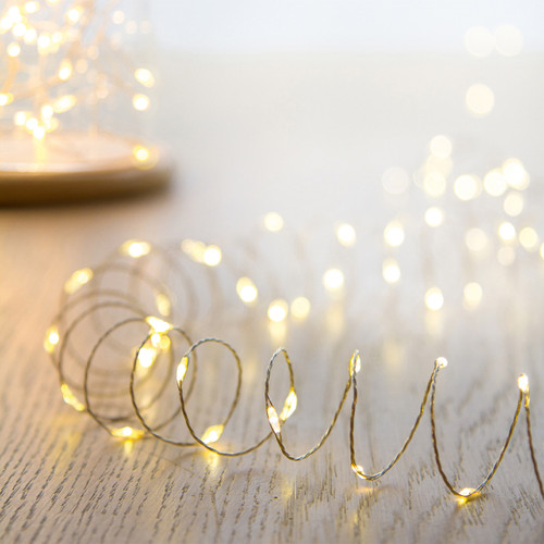 Warm white LED micro wire fairy lights on flexible silver wire, creating a soft ambient glow for Christmas trees, table centrepieces, wreaths and festive indoor décor.