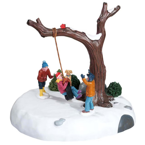 Children playing in the snow around a tree swing, with a dog nearby and snow-covered ground creating a cosy winter scene.
