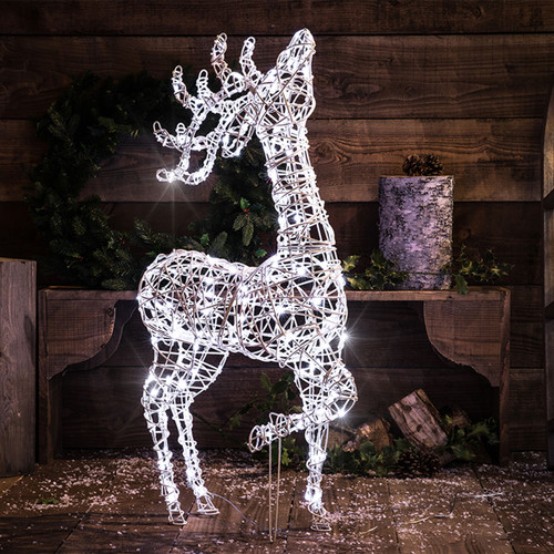 A wicker framed reindeer in front of a wooden bench