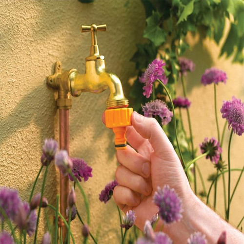 Hozelock tap connector shown being attached to an outdoor garden tap, providing a quick connection for compatible hose fittings.