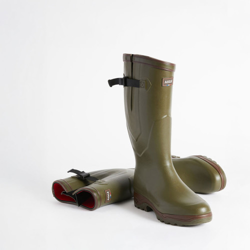 Olive green rubber wellington boots with black buckle straps and red interior lining against a white background. Sturdy and sleek, they convey durability.