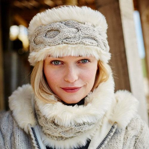 Woman with blonde hair wears a cosy grey knit headband and matching scarf with faux fur lining. She is outdoors, conveying warmth and comfort.