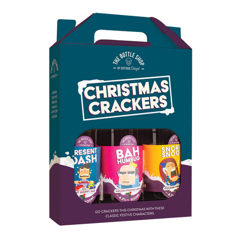 A festive gift pack featuring three cartoon-themed Christmas cracker bottles in colorful wrappers. Labels read "Present Mash," "Bah Humbug," and "Snoring Snoozer."
