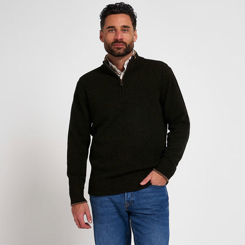 Man wearing a dark olive quarter-zip knitted jumper layered over a checked shirt with blue jeans.
