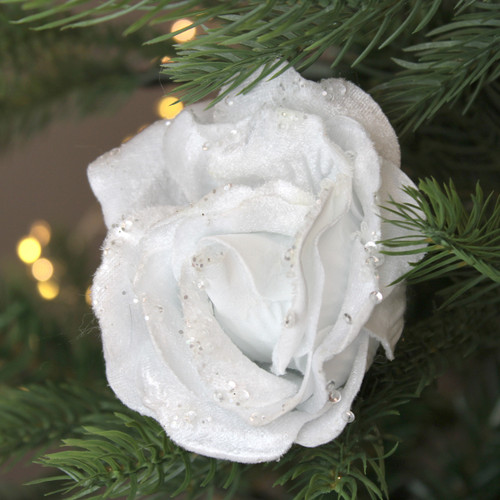 A view of a white velvet rose clip on decoration on a Christmas tree