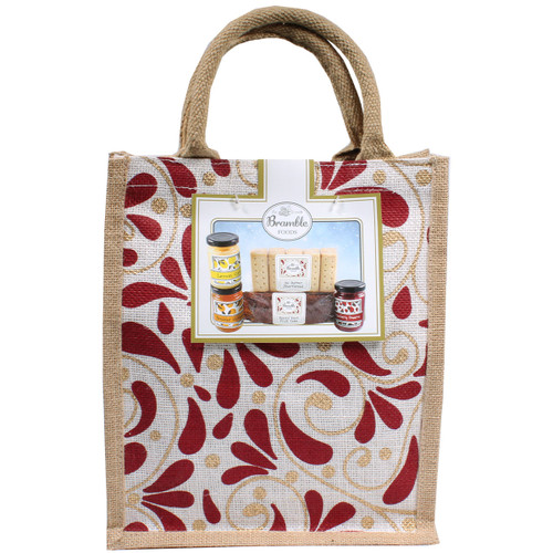 Gift bag featuring a window displaying shortbread, fruit cake, and preserves. The bag has red and gold leaf patterns and two sturdy handles.