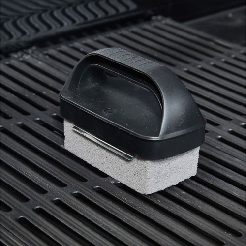 Barbecue cleaning stone with a black grip handle resting on cast iron grill grates.