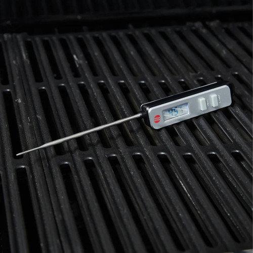 Digital BBQ probe thermometer resting on a grill grate, display showing temperature.