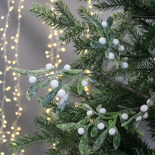 Festive branches with frosted green leaves and white berries, set against a backdrop of warm, glowing fairy lights, creating a calm, wintery ambiance.