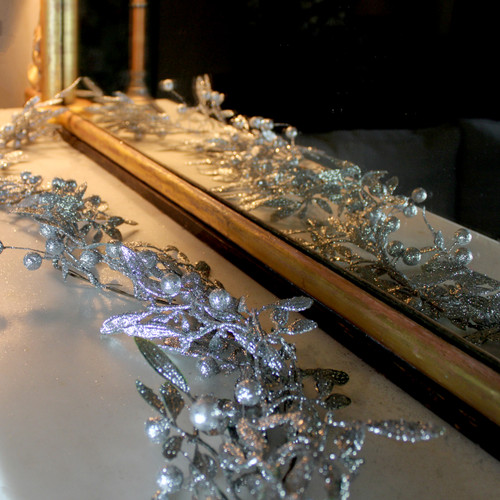 A Silver Glitter Mistletoe Christmas Garland on a mantlepiece with a mirror in the background.