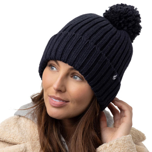 A woman wearing a navy knitted hat with a pompom at the top.