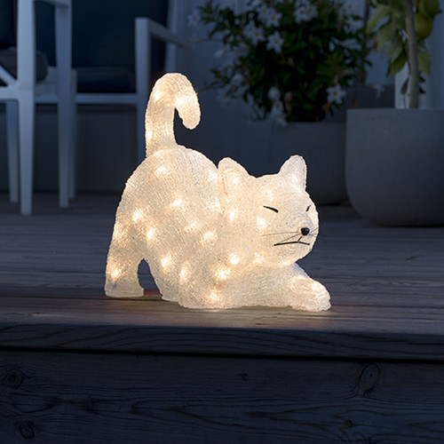 Illuminated LED cat decoration in a playful stretching pose, crafted from sparkling acrylic with warm white lights, displayed outdoors on a wooden deck.
