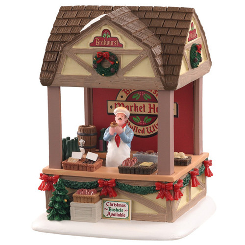 Christmas village market stall with festive garlands, wreath decorations, sausages on display and a vendor serving seasonal food.