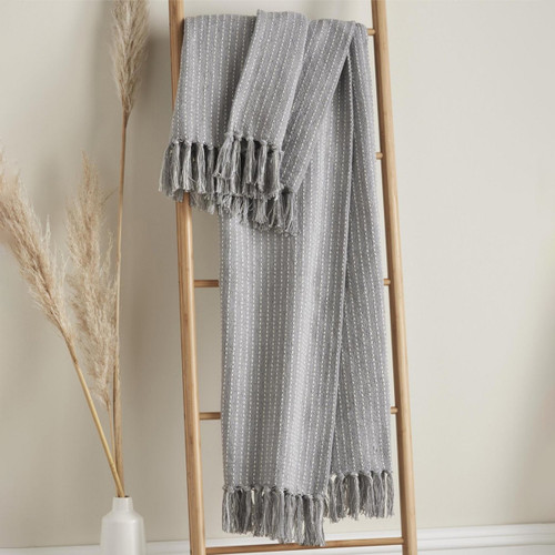 A grey and white throw hung up on a blanket ladder