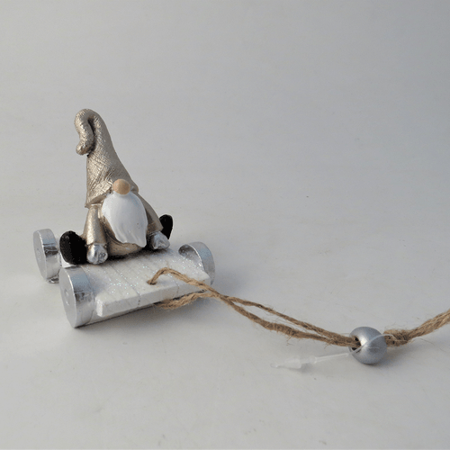 A hanging decoration that is a gonk on a grey sledge.