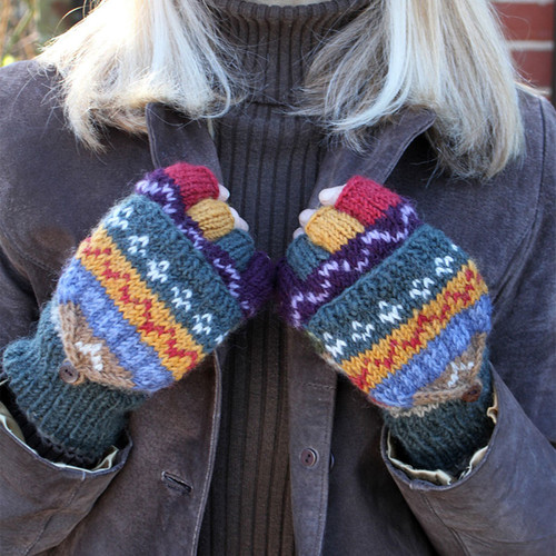A person wearing colourful, patterned mittens, with multicoloured stripes, holds them together. The tone is cosy and warm against a brown jacket. A person wearing colourful, patterned mittens, with multicoloured stripes, holds them together. The tone is cosy and warm against a brown jacket.