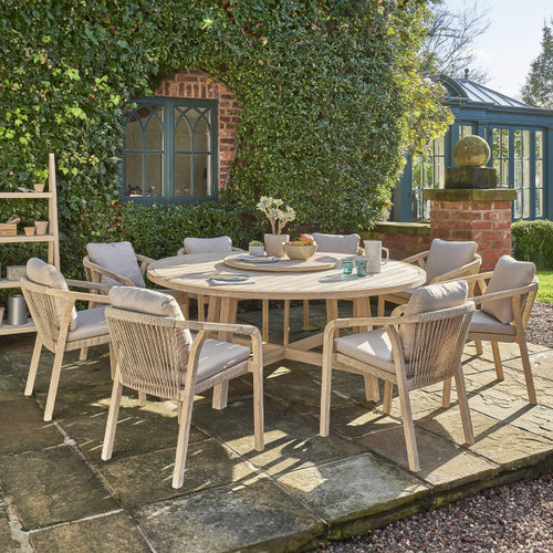 A view of a wooden dining set next to a building with greenery on it