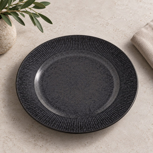 Charcoal grey reactive glaze dinner plate with textured linear rim styled on a dining table