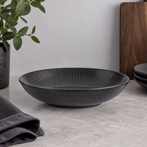 Charcoal grey reactive glaze pasta bowl with textured linear detailing styled on a kitchen worktop