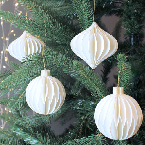 4 white paper decorations in different shapes hanging on a tree