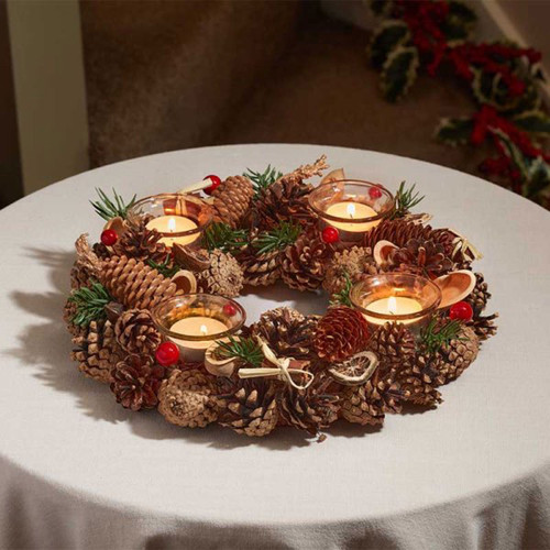 A wreath style candle holder with pine cones, green foliage, red berries and four glass tealight holders.