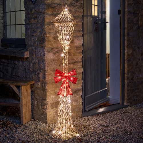 An LED lamp post with a bow in front of a partly opened door