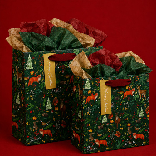 Two dark green Christmas gift bags with red ribbon handles, festive woodland animal prints and red, green and gold tissue paper.