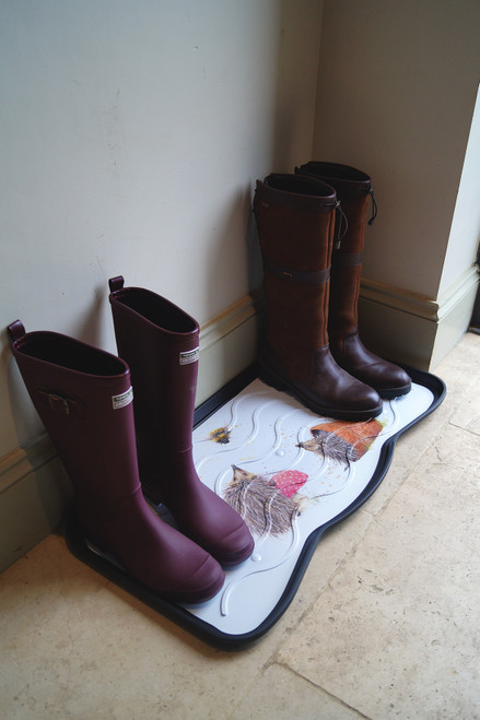 Two pairs of boots sit neatly on a white, decorative rubber mat with animal prints. The scene conveys a cosy, organized entryway.
