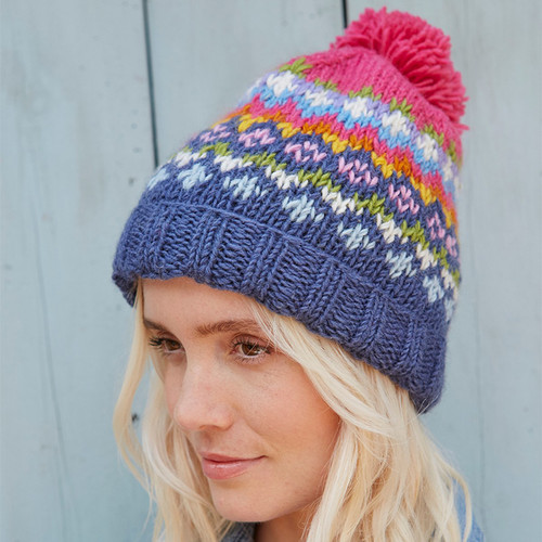 A woman wearing a multicolour fair isle knit hat with a pink bobble on top.