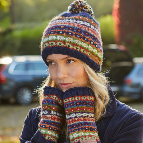 A woman wearing knit fair isle hand warmers with her hands on her face and wearing a matching fair isle knit beanie.