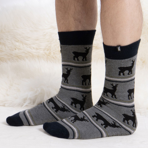 Someone wearing grey slipper socks with stags on them.