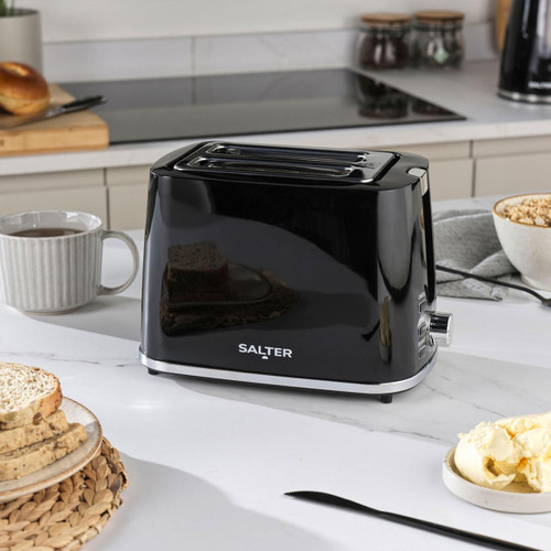 Black toaster on a kitchen counter with bread slices and butter nearby.